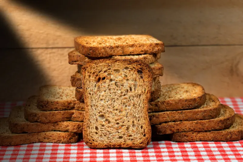 biscottes-de-farine-complète-groupe-saines-sur-une-table-avec-la-nappe-à-carreaux-rouge-et-blanche-le-mur-en-bois-83126123
